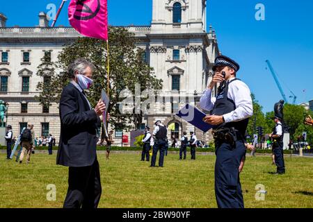 30. Mai 2020 London, UK - Extinction Rebellion inszeniert schweigenden sozial distanzierten Klimawandel-Protest in Westminster, Demonstranten, die von der Polizei wegen Verletzung der Coronavirus-Vorschriften bestraft und weggenommen werden Stockfoto