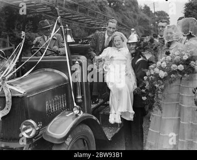 Die Hochzeit des Feuerwehrmändes von Herrn L Garland und Fräulein C Magee . Die Braut und Bräutigam mit der Feuerlöschmaschine . Feuerwehrmann gibt Hilfe für die Braut. 1939 Stockfoto