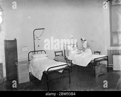 Das Sidcup Cottage Hospital in Kent. Eine Krankenschwester neigt zu einem Patienten in der Männerabteilung. 1939 Stockfoto