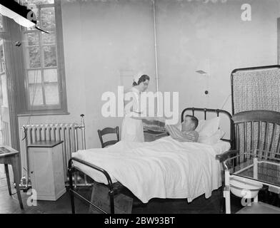 Das Sidcup Cottage Hospital in Kent. Eine Krankenschwester neigt zu Herrn Frank Ager, ein Patient in der Männerabteilung. 1939 Stockfoto