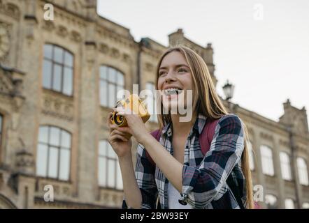 Junge Frau Tourist Foto auf Retro-Kamera. Porträt eines professionellen Fotografen mit gelber Kamera Stockfoto