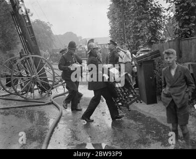 Feuerwehrleute reagieren auf ein Hausfeuer in Chislehurst, Kent. Feuerwehrleute und Polizist versuchen und retten Möbel aus dem Haus. 1939 Stockfoto