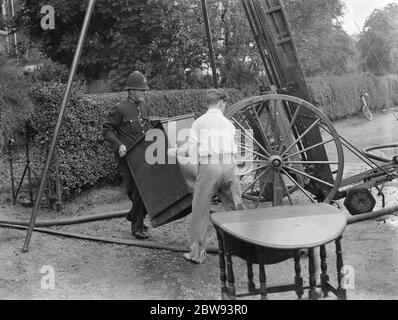 Feuerwehrleute reagieren auf ein Hausfeuer in Chislehurst, Kent. Ein Polizist versucht, Möbel aus dem Haus zu retten. 1939 Stockfoto