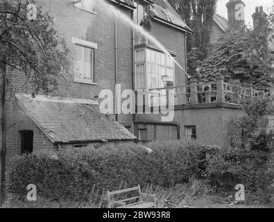 Feuerwehrleute reagieren auf ein Hausfeuer in Chislehurst, Kent. Eine Feuerwehr schlaucht Wasser in das obere Fenster des Gebäudes. 1939 Stockfoto