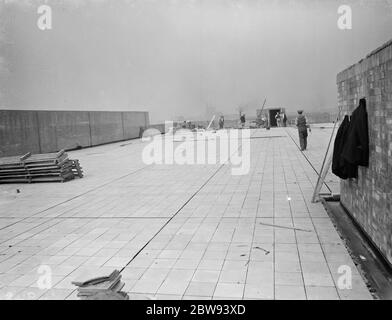 Arbeiter von Val De Travers Asphalt Limited, ein Pflasterunternehmen, arbeiten auf einem Dach in Greenwich, London. 1938 Stockfoto