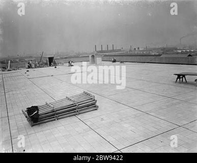 Arbeiter von Val De Travers Asphalt Limited, ein Pflasterunternehmen, arbeiten auf einem Dach in Greenwich, London. 1938 Stockfoto