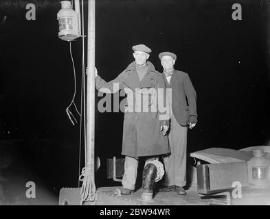 Zwei Männer blicken vom Deck eines Schiffes auf den Ort einer Kollision auf der Themse. 1937 Stockfoto