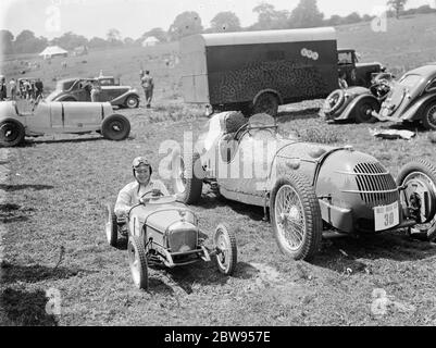 Peter McClure sitzt in einem Spielzeug-Rennwagen, neben der realen Sache geparkt, in Lullingstone, Kent. 1936 . Stockfoto