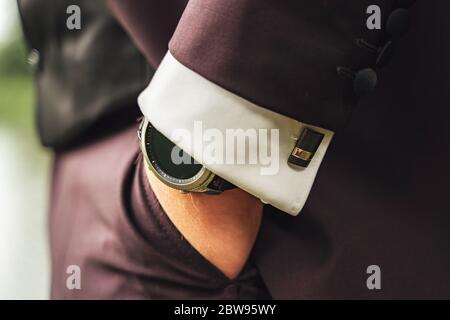 Bräutigam im perfekten Anzug. Nahaufnahme der Hand in der Tasche. Businessman in Burgunder Anzug und weißem Hemd mit Manschettenknöpfen. Uhren am Handgelenk. Stockfoto