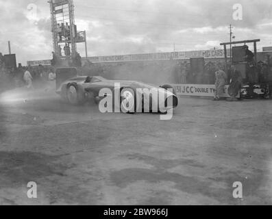 Sir Malcolm Campbell beschädigt Reifen auf Brooklands Betonspur. Der Bluebird Out in Brookland machte seinen Auftritt auf der Brooklands Strecke am Ostermontag, Bank Holiday Eröffnungstreffen, die einzige Gelegenheit, bei der das Auto in England unter seiner eigenen Macht und mit Sir Malcolm Campbell am Steuer gesehen werden. Sir Malcolm zog die Reifen bei seinem ersten Lauf von den Rädern ab, als er sich auf der Betonspur akzellierte. Sir Malcolm Campbell in seinem Bluebird, der die Brooklands-Strecke umrundet. 28 März 1932 Stockfoto