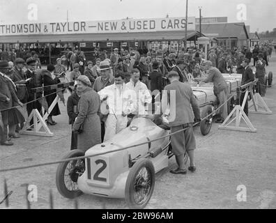 Rennen um British Empire Trophäe in Brooklands . Viele berühmte britische Rennfahrer Reihen sich am Start des British Racing Drivers Club , Empire Trophy Race , auf dem Brooklands Track , Weybridge , Surrey . Die Szene im Fahrerlager als die Autos zur Startlinie gingen. 30. April 1932 Stockfoto