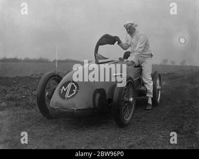 G E T Eyston bereitet sich auf Angriff auf Weltrekord für Baby-Autos in Pendine Sands . Herr G E T Eyston, der Rennfahrer, macht die letzten Vorbereitungen für seinen Versuch, einen neuen Weltrekord für Baby-Autos mit seinem MG The Magic Midget, die auf Pendine Sands, Carmarthenshire, Wales stattfinden wird. Er wird einen speziell angefertigten Asbestanzug tragen. Herr G E T Eyston trägt seine Asbestkleideranzug, Eingabe seines Autos durch Anheben der Windhaube, das Cockpit ist gemacht, um ihn zu passen, bevor das Auto seine Abingdon-Garage verlassen, Berkshire, für Pendine. Februar 1932 Stockfoto