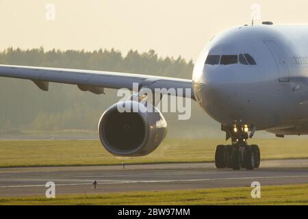 Nahaufnahme eines Großkörperflugzeugs, das während des Sonnenuntergangs auf der Landebahn rollt. Flugzeug schaltet auf Start- und Landebahn. Sehr heiße Luft hinter dem Flugzeugmotor. Transpor Stockfoto