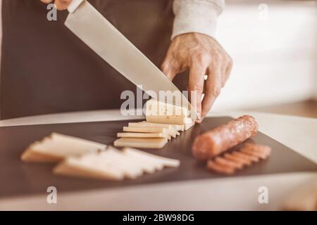 Bis zu schließen. Mann schneiden Käse Sandwiches Stockfoto