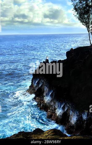 Die lokalen Fischer stehen auf den Felsen für eine Nacht des Fischens. Er sitzt am Rande eines Felsvorsprünges im McKinzie State Park auf der Big Island of H Stockfoto