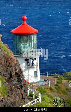 Zwei Arbeiter malen das Äußere des Makapuu Point Leuchtturms auf der Insel Oahu, Hawaii. Azure Wasser Rahmen Klippe und Licht. Stockfoto