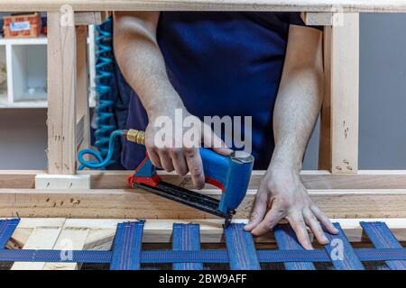 Herstellung von Möbelsitzen. Professionelle männliche Tischler Polsterung Vintage Sessel in der Werkstatt. Stockfoto