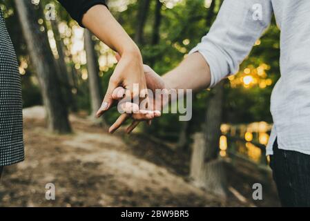 Nahaufnahme von den verschlungenen Hände von ein Paar in Liebe zu Fuß durch den Wald. Stockfoto