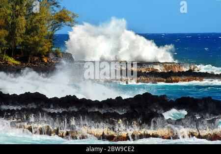 Große Welle trifft die schwarze Lavaküste des Mackenzie State Park auf der Big Island von Hawaii. Stockfoto