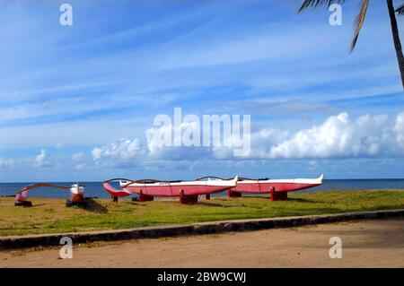 Outrigger Kanus sitzen am Nordufer der Insel Oahua. Jeder ruht auf einer Reifenstütze, eingerahmt von Meer und Wolken. Stockfoto