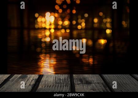 Top aus schwarzem Holz Tisch in Bar oder Pub mit Blur Bokeh abstrakten Stadt Licht in der dunklen Nacht für Party oder festlichen Hintergrund Stockfoto