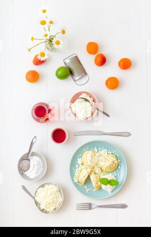 Mit Aprikosen gefüllte Fruchtknödel, bestreut mit Quark und Zucker, übergossen mit geschmolzener Butter, mit Creme fraiche mit geriebener Limettenschale an Stockfoto