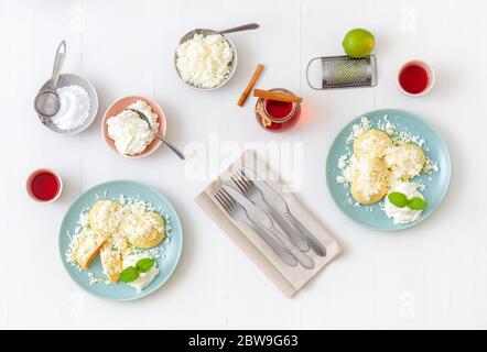 Mit Aprikosen gefüllte Fruchtknödel, bestreut mit Quark und Zucker, übergossen mit geschmolzener Butter, mit Creme fraiche mit geriebener Limettenschale an Stockfoto