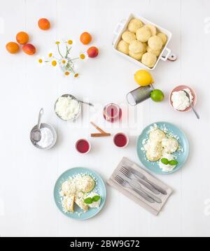 Mit Aprikosen gefüllte Fruchtknödel, bestreut mit Quark und Zucker, übergossen mit geschmolzener Butter, mit Creme fraiche mit geriebener Limettenschale an Stockfoto