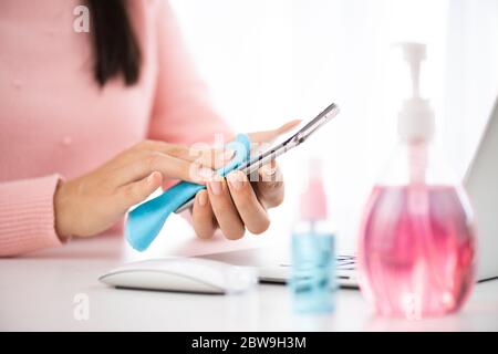 Nahaufnahme Hände reinigen den Smartphone-Bildschirm mit einem Fasertuch von Schmutz Staub und Virus, gegen Coronavirus oder Corona-Virus-Krankheit (Covid-19) Stockfoto