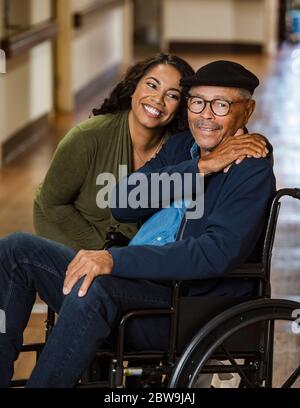 Tochter umarmt älteren Vater im Rollstuhl Stockfoto