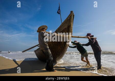 HOI AN - APR 06, 2017: Vietnamesische Fischer schieben ein Fischerboot an einem sonnigen Tag am 04. April 2017 in Hoi an, Vietnam Stockfoto