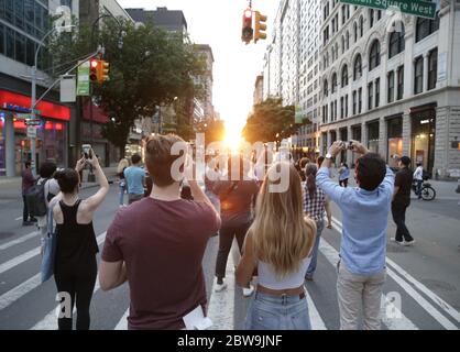 New York, Usa. Mai 2020. Zuschauer fotografieren die untergehende Sonne am Samstag, den 30. Mai 2020, in der 14th Street in New York City. Die untergehende Sonne richtet sich mit dem Ost-West-Gitter von Manhattan in einem Phänomen, das zweimal im Jahr geschieht und als Manhattanhenge bezeichnet wird. Foto von John Angelillo/UPI Quelle: UPI/Alamy Live News Stockfoto