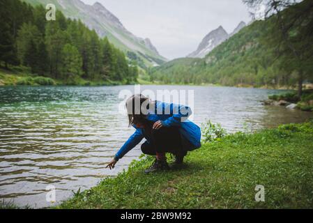 Schweiz, Bravuogn, Palpuognasee, Junge Frau hockt byÂ Palpuognasee in Schweizer Alpen Stockfoto