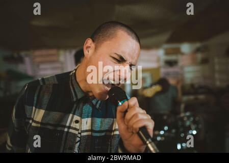 Junger Mann singt während der Probe in der Garage Stockfoto