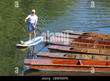 Cambridge, Großbritannien. Mai 2020. Ein Paddelboarder treibt an einer der zahlreichen Punt-Stationen der Stadt am River Cam vorbei.Cambridge, eine Stadt, die für ihre Punt-Stations berühmt ist, kann Touristen nach den aktuellen Regierungsrichtlinien nicht den Service anbieten. Scudamores, die größte Punt Hire Company der Stadt, hat den Betrieb eingestellt und die vielen Punt-Stationen der Stadt stehen aufgrund der Coronavirus-Pandemie ungenutzt. Quelle: SOPA Images Limited/Alamy Live News Stockfoto