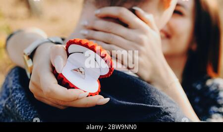 Erfolgreiche Anfrage nach der Ehe eines kaukasischen Mannes mit rotem Ring Box umarmt von seiner zukünftigen Frau Stockfoto