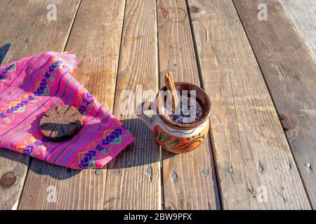 Mexikanische Schokolade champurrado mit Zimt in traditionellen Tonbecher und mexikanischen Sarape Stockfoto