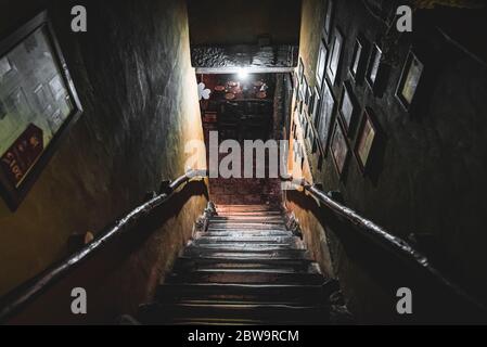 VILLA GESELL, ARGENTINIEN, 14. NOVEMBER 2019: Dramatische Sicht auf die schaurige Treppe von oben in die Dunkelheit des Innenraums des alten Pubs Stockfoto