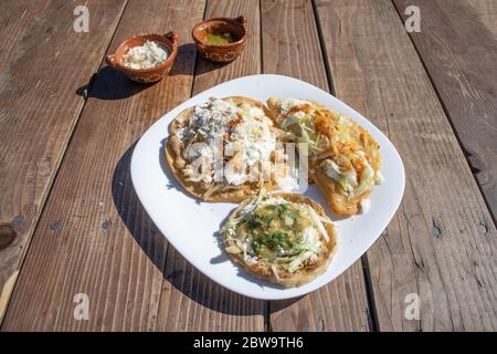 Teller mit einer Vielzahl von mexikanischen Speisen wie Sope, Tacos und Quesadilla mit Sauce Stockfoto