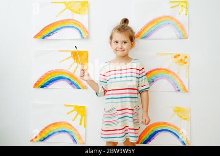Porträt von glücklichen Vorschulmädchen vor Regenbogenbildern an der Wand Stockfoto