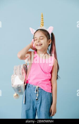 Porträt eines glücklichen kleinen Mädchens, das am Telefon über blau spricht Stockfoto