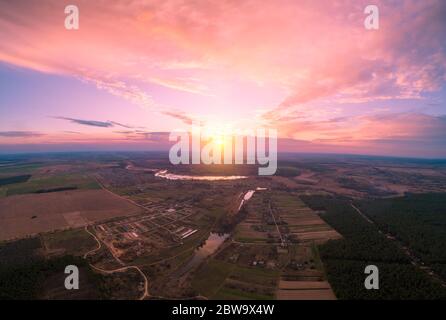 Frühling ländliche Landschaft. Das Dorf am Abend. Vogelperspektive. Panoramablick auf das Dorf, Felder, Pinienwald und Fluss bei Sonnenuntergang. Panorama Stockfoto