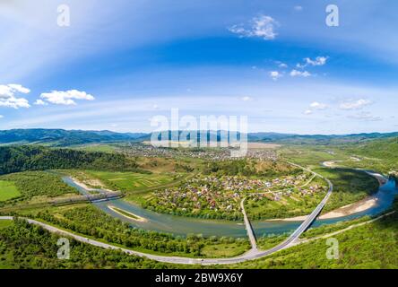 Panorama-Blick aus der Luft auf die Berge, den Fluss und das Dorf im Tal im Frühling. Skyline, wunderschöne Naturlandschaft. Karpaten. Ukraine Stockfoto