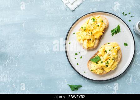 Rührei auf Toast, Draufsicht, Kopierplatz. Hausgemachtes Frühstück oder Brunch-Menü - Rührei Sandwiches. Stockfoto