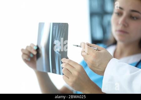 Frau schaut auf eine Röntgenhand, neben dem Arzt Stockfoto