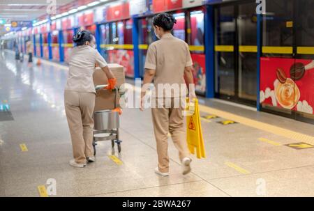 Die beiden Dienstmädchen tragen chirurgische Maske und Reinigungshandschuh Vorbereitung auf große Reinigung für Hygiene an der U-Bahn-Station. Für das neue Normalkonzept. Stockfoto