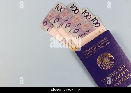 Weißrussischer Pass und neue Banknoten in der Republik Belarus mit dem Nennwert von hundert Rubel. Separat auf blauem Hintergrund. Stockfoto