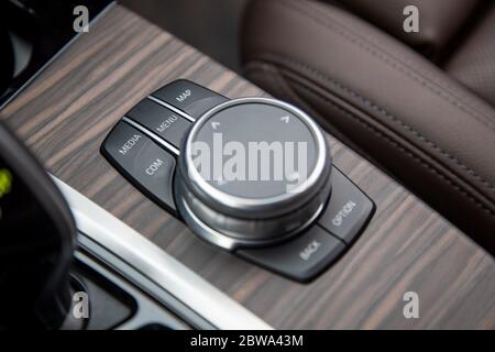 Nahaufnahme von Bedientasten des Multimedia-Systems auf einer Holzplatte in einem modernen Premium-Luxusauto. Nahaufnahme, weiche Fokussierung. Stockfoto