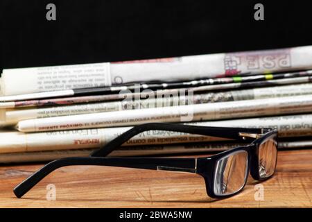 Gefaltete Stapel Zeitungen mit einem Paar blaue Lesebrille darauf. Kostenlose Informationen und Presse Konzept Stockfoto