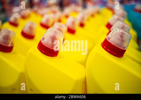 Reihen von gelben Plastikflaschen mit einem roten Verschluss wirh Haushalt Chemikalien. Nahaufnahme, weiche Fokus, Hintergrund in Unschärfe Stockfoto